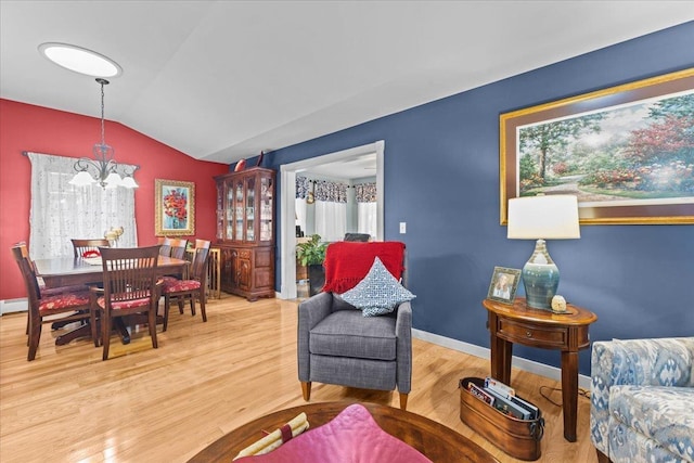 living room featuring a notable chandelier, baseboards, vaulted ceiling, and wood finished floors