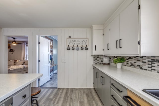 kitchen featuring light countertops, light wood-type flooring, gray cabinets, and decorative backsplash