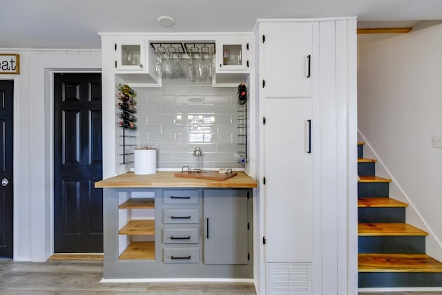 bar with tasteful backsplash, visible vents, stairway, and wood finished floors