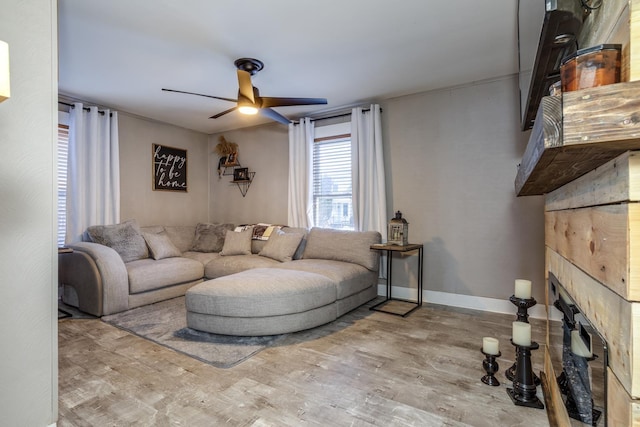 living area with ceiling fan, a fireplace, baseboards, and wood finished floors