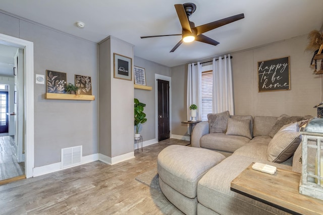 living room with a wealth of natural light, wood finished floors, visible vents, and a ceiling fan