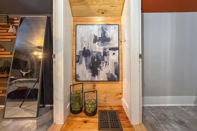 hallway with visible vents, wooden walls, baseboards, and wood finished floors