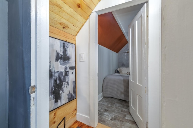 hallway with lofted ceiling, wood finished floors, and baseboards