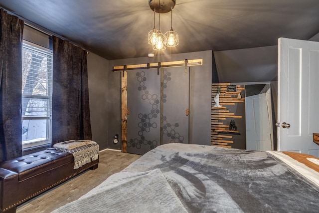 bedroom with a barn door, multiple windows, and wood finished floors