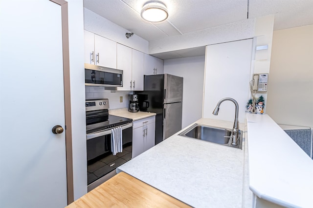 kitchen with wood finished floors, a sink, light countertops, appliances with stainless steel finishes, and decorative backsplash