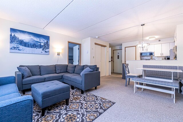 living room featuring a chandelier, light colored carpet, and a textured ceiling