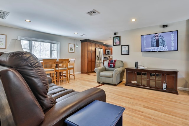 living area featuring baseboards, light wood-type flooring, visible vents, and recessed lighting