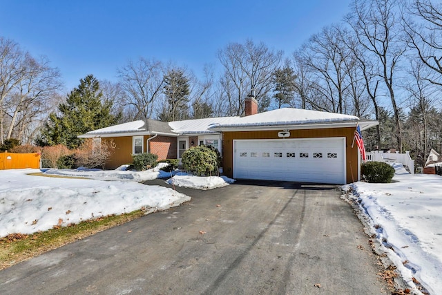 single story home featuring a garage, driveway, brick siding, and a chimney