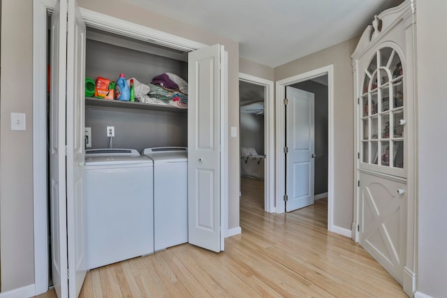 laundry area with laundry area, baseboards, light wood-style flooring, and washing machine and clothes dryer