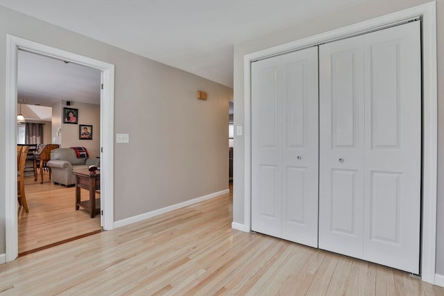 bedroom with light wood-type flooring, a closet, and baseboards