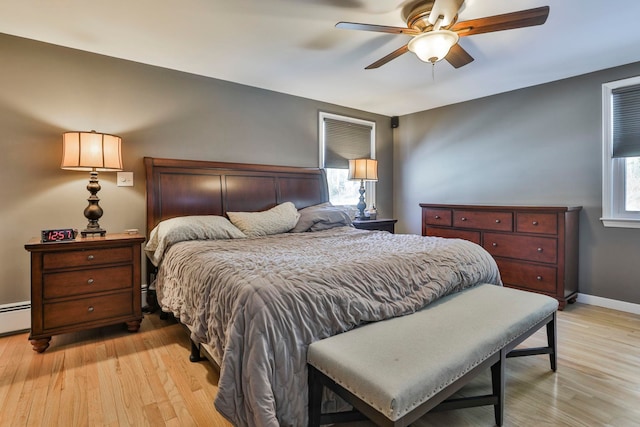 bedroom with ceiling fan, multiple windows, light wood-type flooring, and baseboards