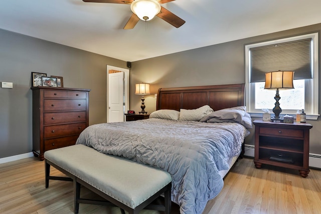 bedroom featuring a baseboard heating unit, light wood-style flooring, baseboards, and a ceiling fan