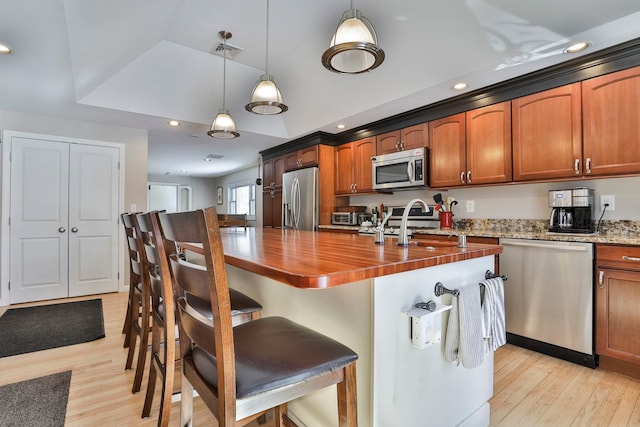 kitchen with appliances with stainless steel finishes, light wood-type flooring, a sink, and visible vents