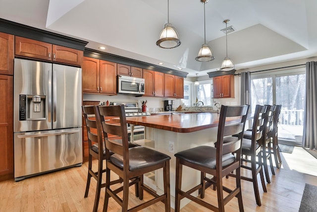 kitchen with stainless steel appliances, light wood finished floors, a raised ceiling, and visible vents