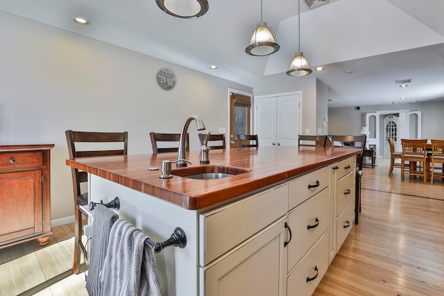 kitchen with light wood-style floors, wood counters, and a sink