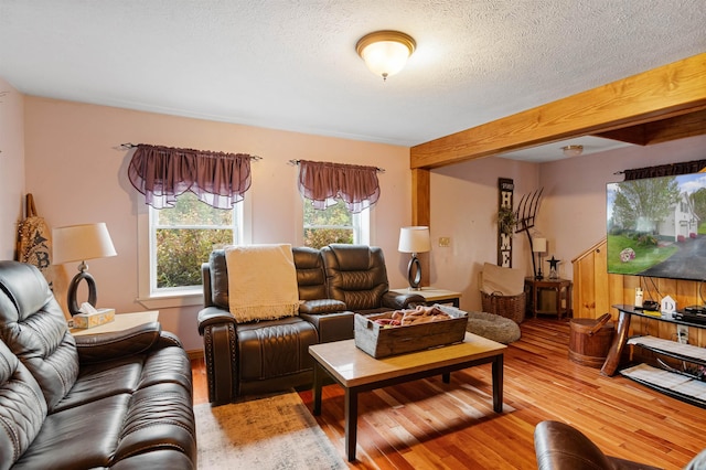 living room with a textured ceiling, beamed ceiling, and wood finished floors