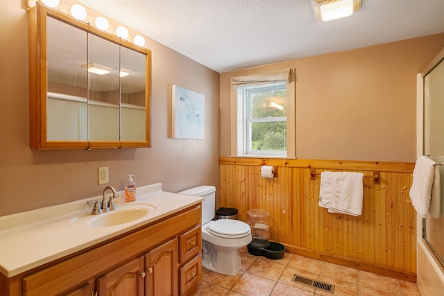 bathroom with visible vents, toilet, wainscoting, wooden walls, and a textured ceiling