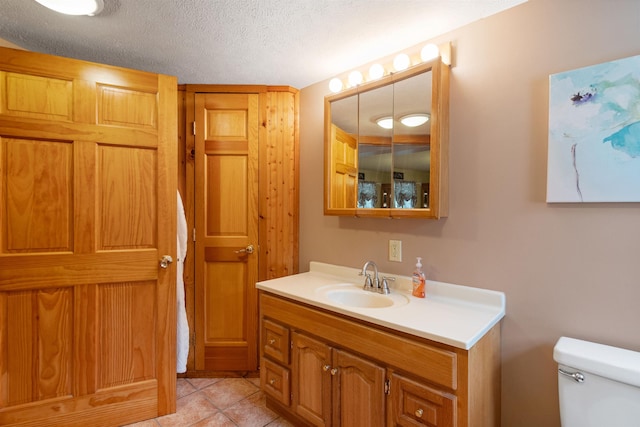 bathroom with tile patterned flooring, a textured ceiling, toilet, and vanity