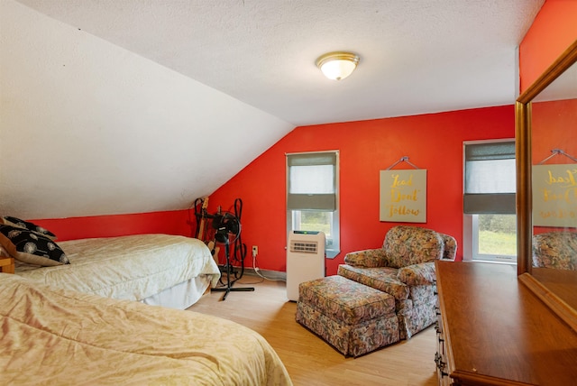 bedroom featuring a textured ceiling, vaulted ceiling, and wood finished floors