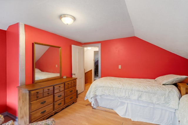 bedroom featuring light wood finished floors and vaulted ceiling