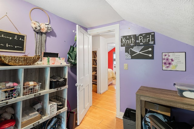 interior space featuring lofted ceiling, a textured ceiling, and wood finished floors