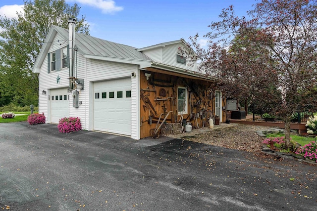 view of home's exterior with metal roof, aphalt driveway, an attached garage, and central air condition unit