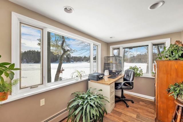 office area featuring a baseboard heating unit, light wood-type flooring, a healthy amount of sunlight, and baseboards