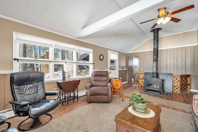 living room featuring lofted ceiling with beams, a baseboard radiator, wood finished floors, a wood stove, and crown molding