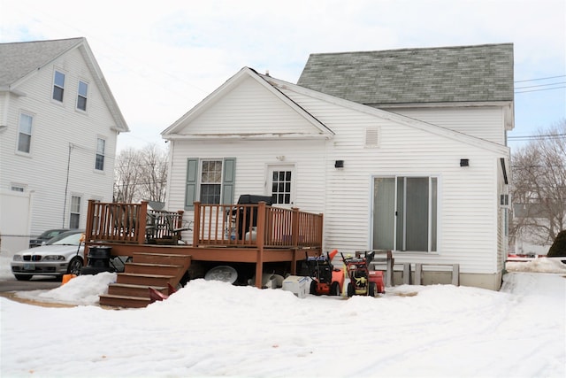 snow covered property with roof with shingles and a wooden deck