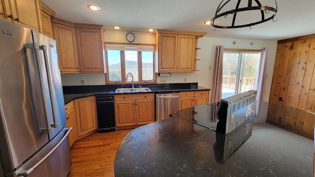 kitchen featuring stainless steel appliances, dark countertops, a sink, and a wealth of natural light