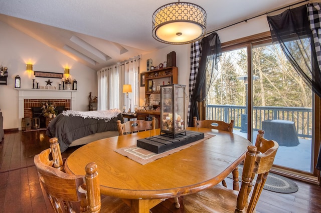 dining space featuring lofted ceiling, a brick fireplace, and hardwood / wood-style flooring