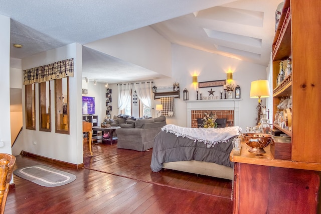 bedroom with a fireplace, wood-type flooring, vaulted ceiling, a textured ceiling, and baseboards