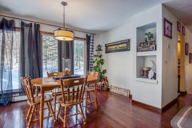 dining space featuring a textured ceiling, baseboards, and hardwood / wood-style floors