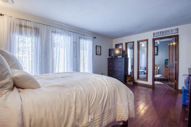 bedroom featuring dark wood-style floors, a textured ceiling, and baseboards