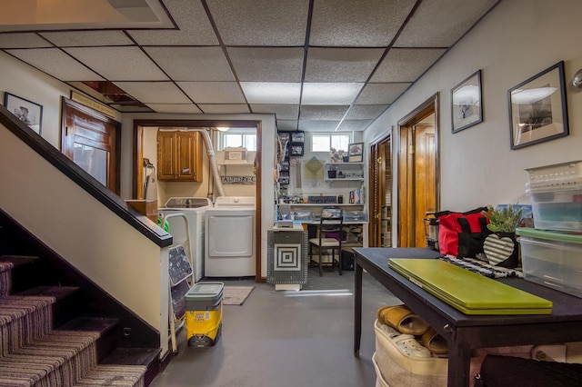 basement featuring a drop ceiling, washing machine and clothes dryer, and stairs