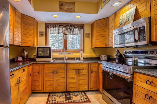 kitchen with brown cabinets, stainless steel appliances, a sink, and recessed lighting