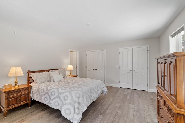 bedroom with baseboards, light wood-style flooring, and multiple closets