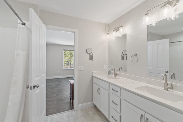 full bathroom featuring double vanity, a sink, and baseboards