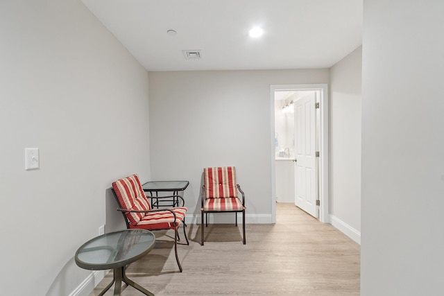 living area featuring wood finished floors, visible vents, and baseboards