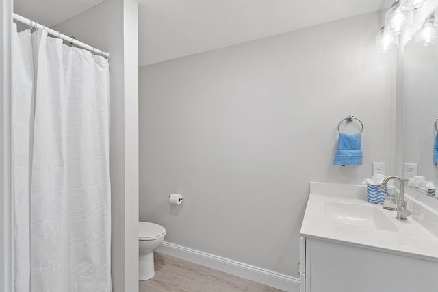 full bathroom with toilet, baseboards, wood finished floors, and vanity