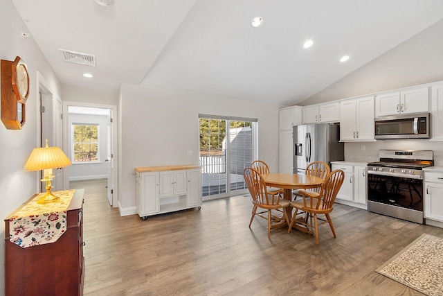 dining space with light wood-type flooring, visible vents, lofted ceiling, and recessed lighting