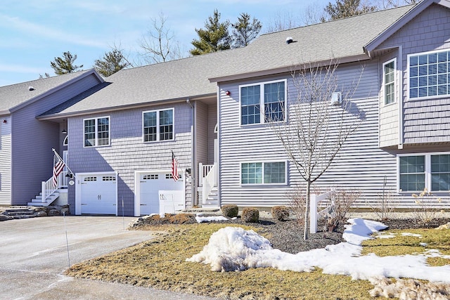 view of front of house featuring a garage, driveway, a shingled roof, and stairs