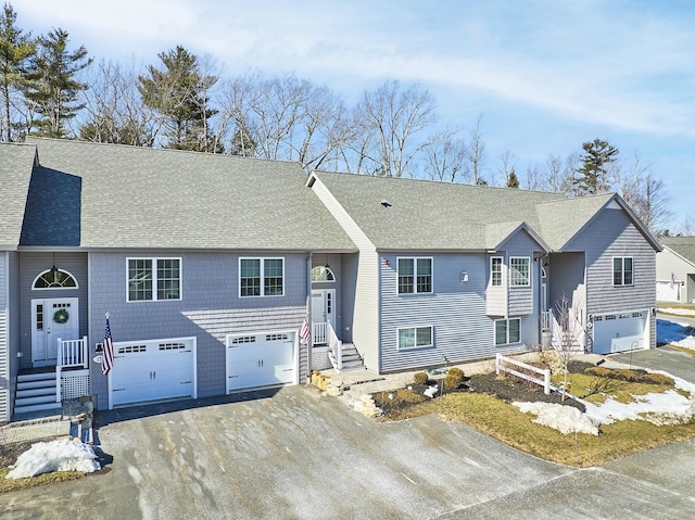 raised ranch featuring aphalt driveway, an attached garage, and a shingled roof