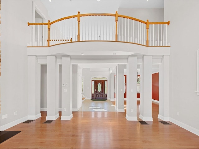 entryway with a high ceiling, wood finished floors, visible vents, and baseboards