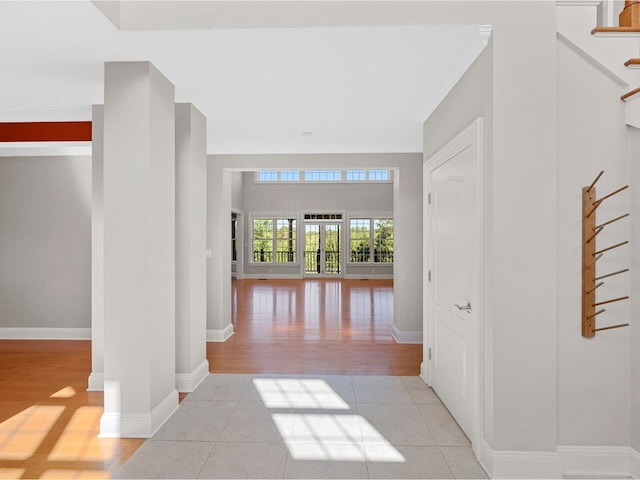 hall featuring stairs, light tile patterned flooring, and baseboards