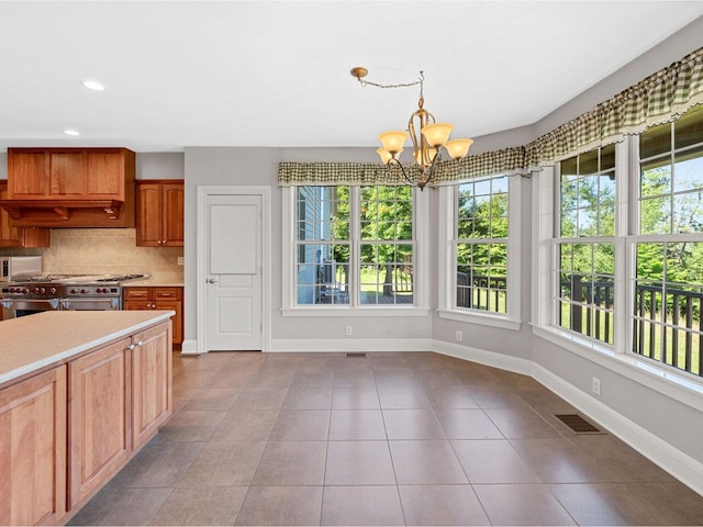 kitchen with light countertops, visible vents, backsplash, double oven range, and baseboards