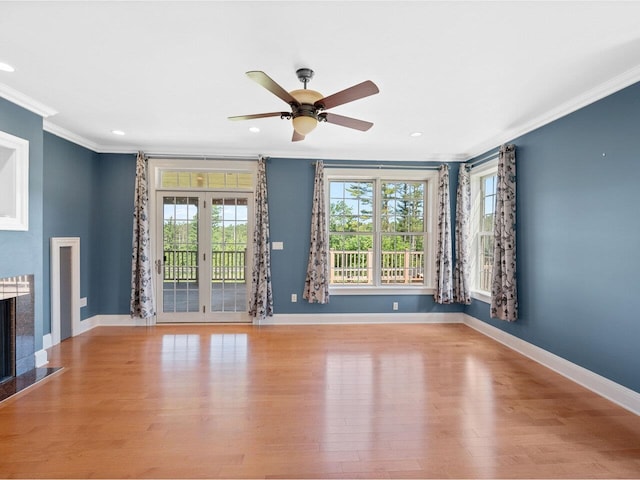 unfurnished living room featuring ornamental molding, a fireplace, baseboards, and wood finished floors