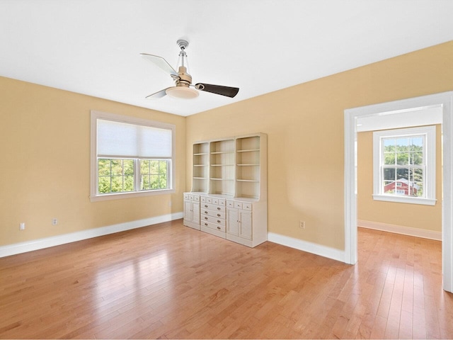 unfurnished bedroom with multiple windows, light wood-style flooring, and baseboards