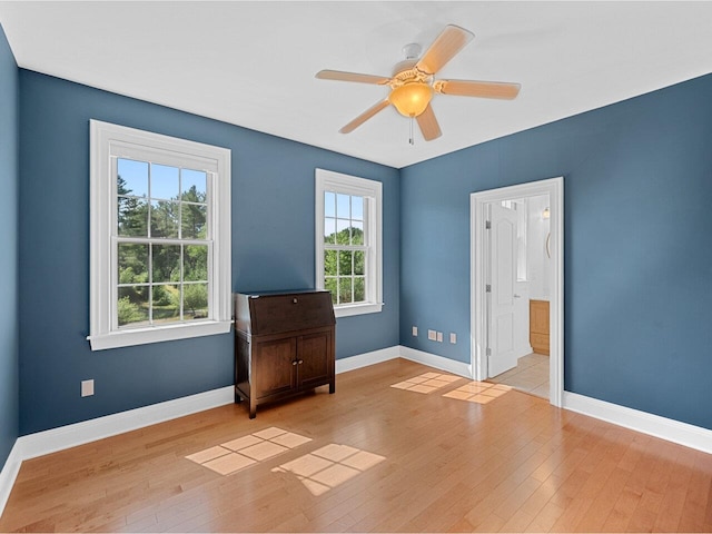 spare room featuring a ceiling fan, a wealth of natural light, wood-type flooring, and baseboards