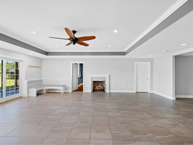 unfurnished living room with crown molding, recessed lighting, a raised ceiling, a warm lit fireplace, and baseboards